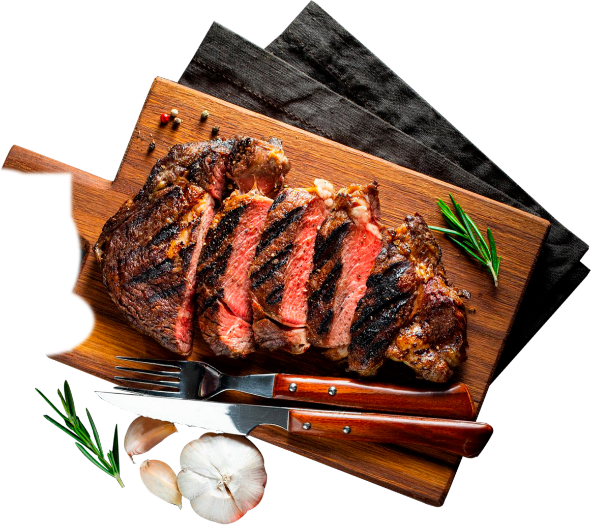 Sliced grilled ribeye on a wooden board with rosemary, garlic and a steak knife